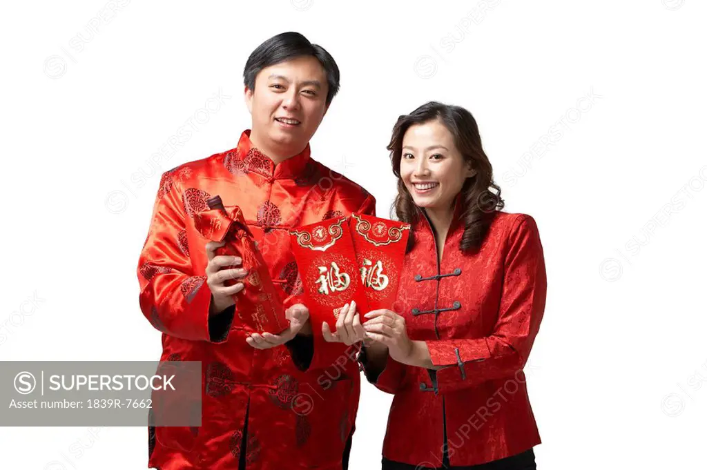 A couple holds gifts and a bottle of wine for Chinese New Year