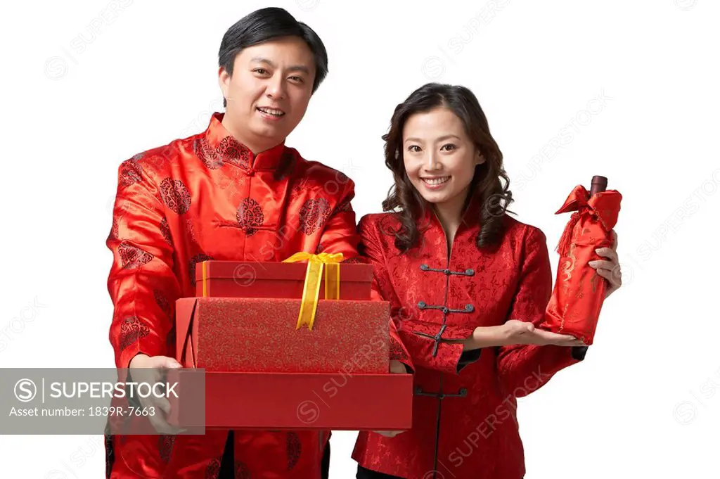 A couple holds gifts of wine and red envelopes for Chinese New Year