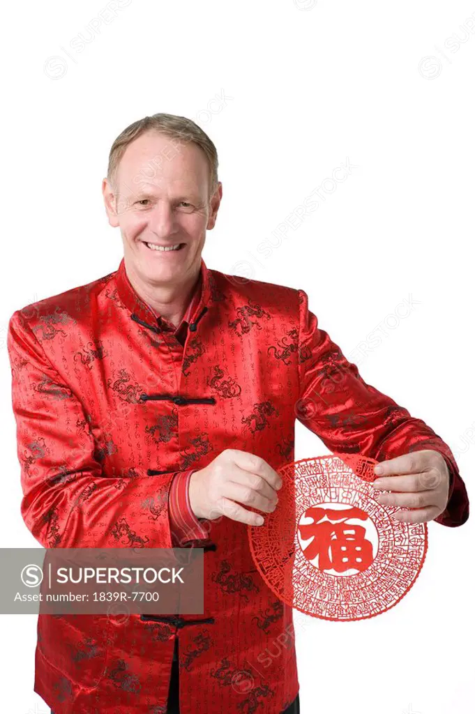 A man holds out a paper cutting with the Chinese character for wealth and happiness
