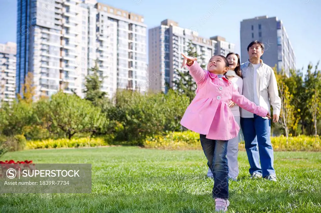 A young girl throws a paper airplane, while her parents look on