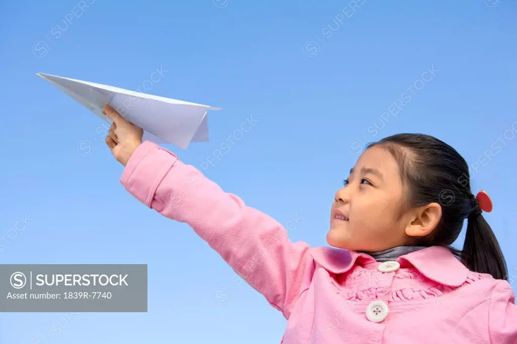 A young girl throwing a paper airplane