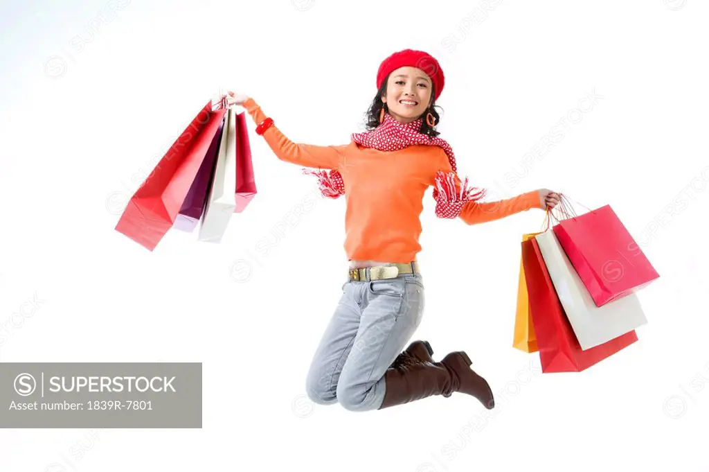 Young woman jumping up with her shopping bags