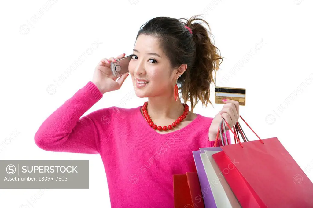 Young woman talking on the phone and holding her credit card