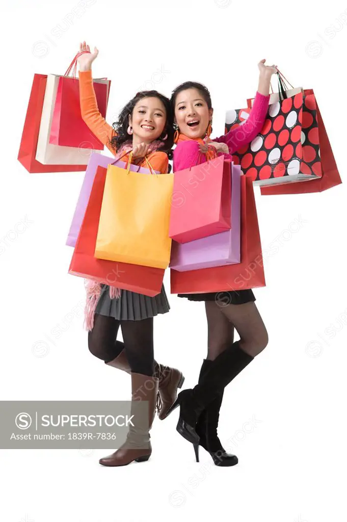 Two young women holding up shopping bags