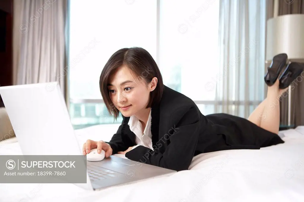 Woman lying in bed and looking at her computer