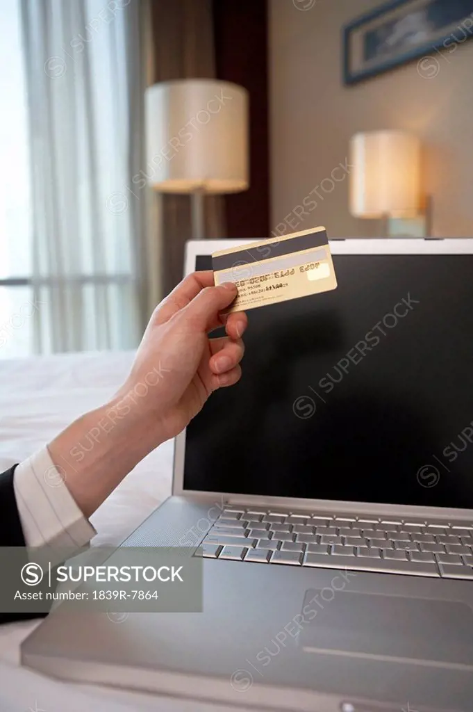 Woman´s hand holding a credit card in front of a computer
