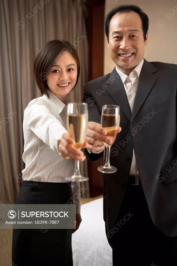Man and woman extending champagne glasses
