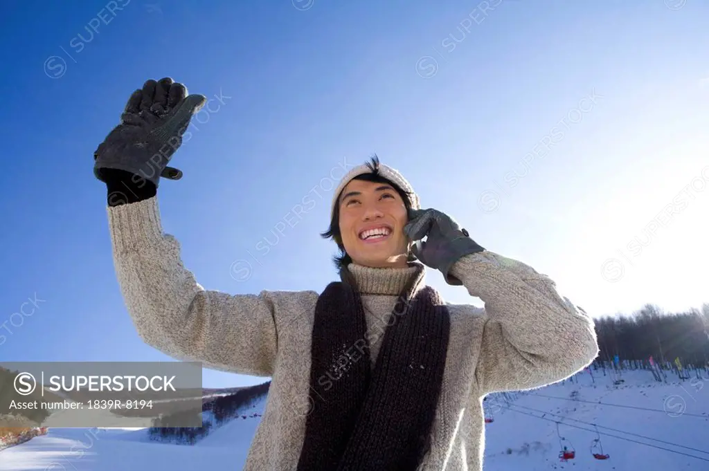 Young man talking on mobile phone and raising his arm