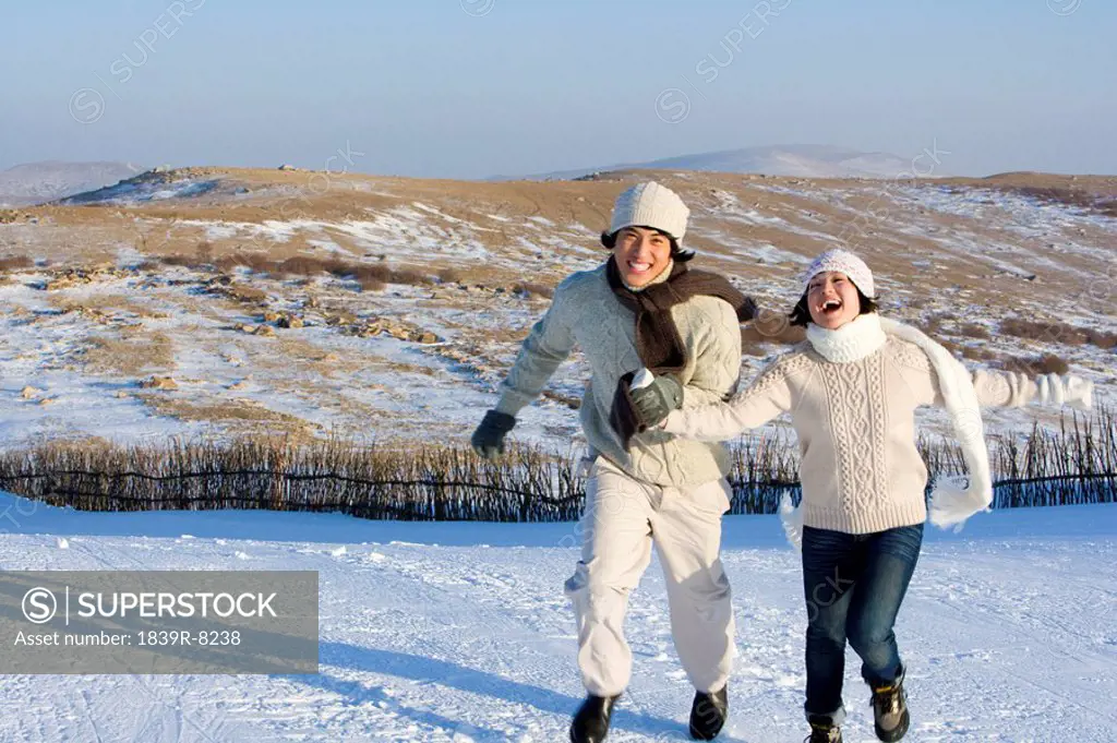 Young man and young woman running in the snow
