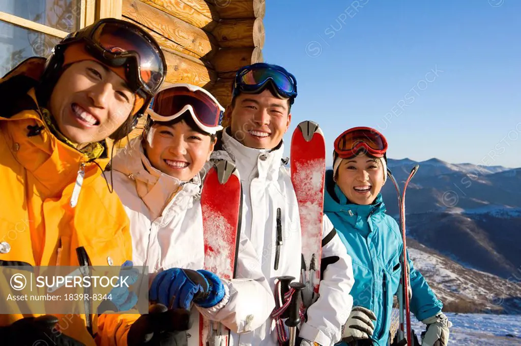 Four young people with their ski equipment