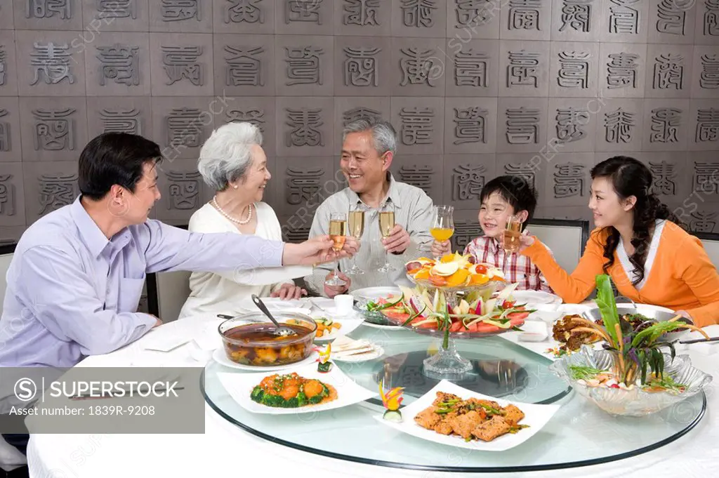 Parents and grandparents with son toasting at dinner table