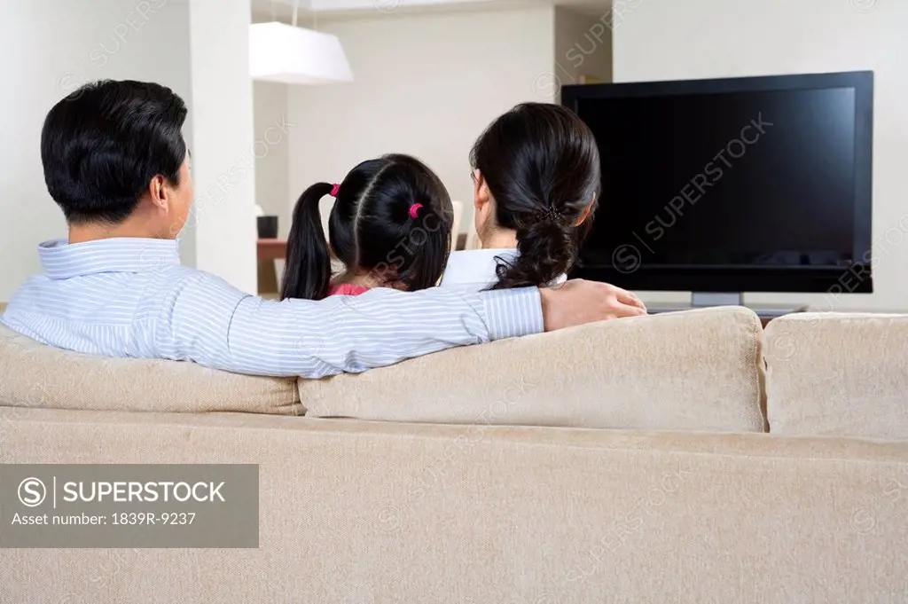 Couple with child in front of widescreen television