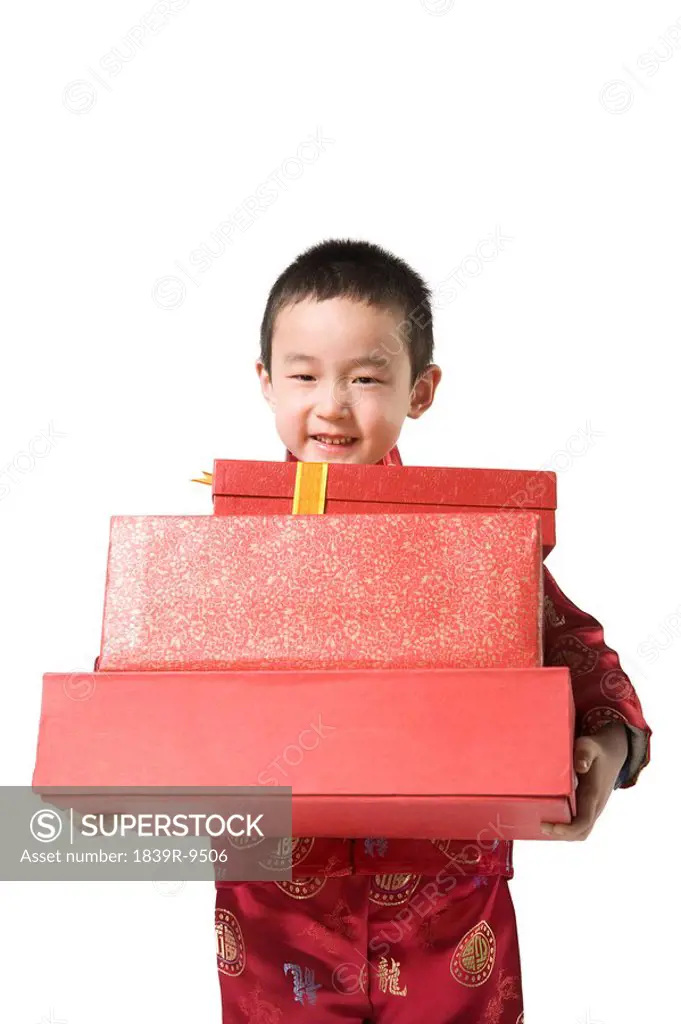 Boy in Chinese traditional clothes holding gift boxes