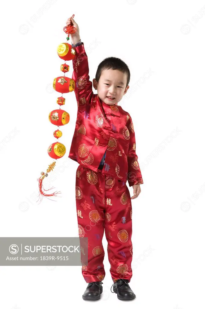 Boy in Chinese traditional clothes holding Chinese New Year decoration