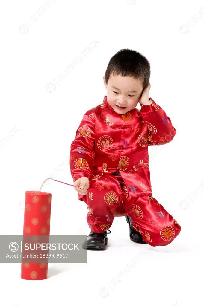 Boy in Chinese traditional clothes playing fireworks