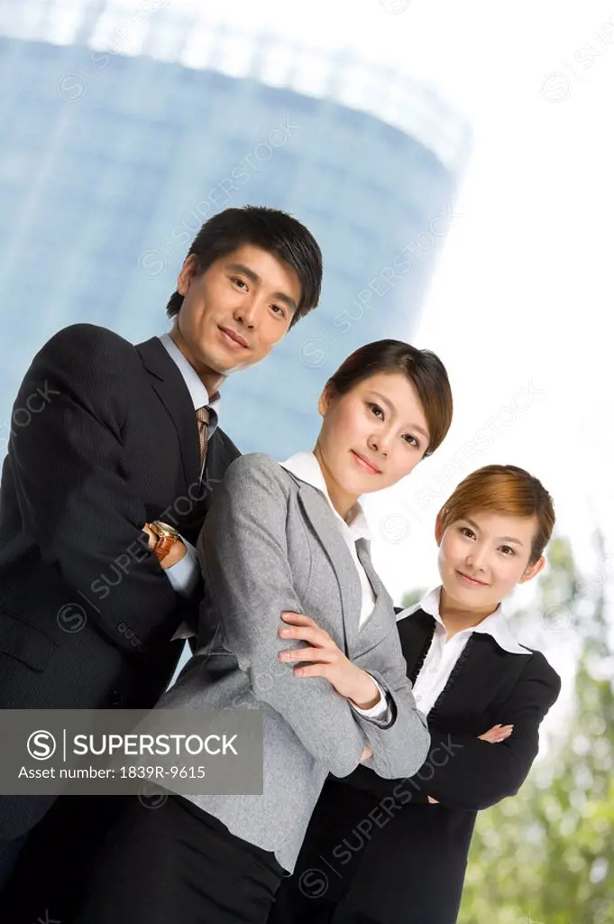 Three business professionals in front of skyscraper