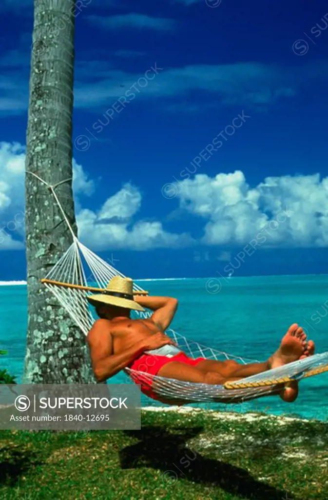 Man in hammock on Matira Beach on the Island of Bora Bora in French Polynesia in the South Pacific Ocean.