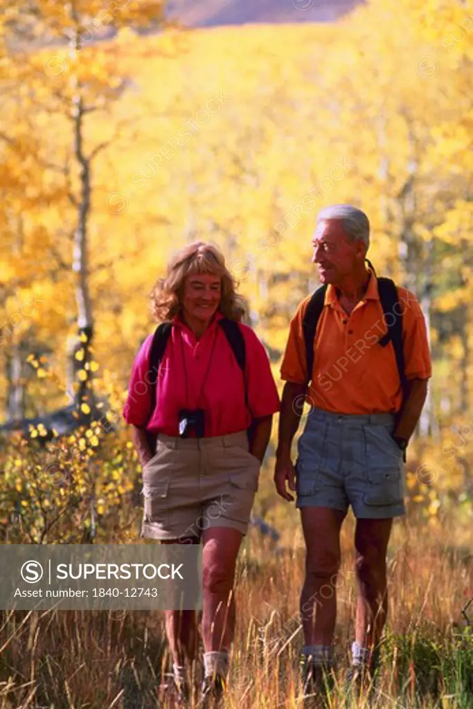 Senior couple walking in autumn woods.