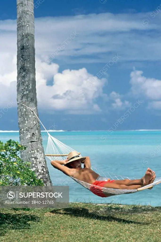 Man in hammock at Matira Beach on island of Bora Bora in French Polynesia in the South Pacific.