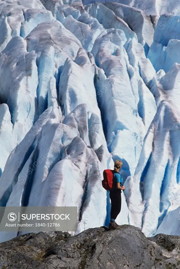 Woman standing on rock overlooking seracs on Mendenhall Glacier near the town of Juneau, Alaska.