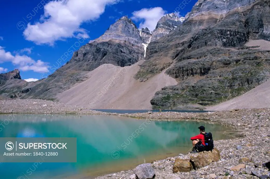 Hiker along the shore of turquoise-colored Little Lake Oesa with Mount Huber (center) in the Lake O'Hara region of Yoho National Park, British Columbia, Canada