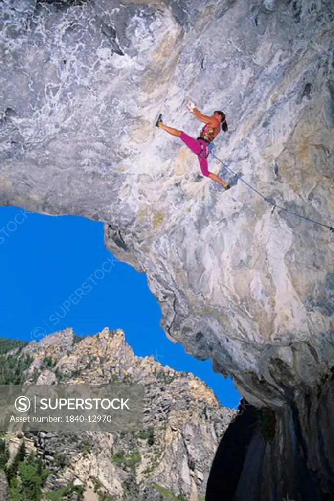 Woman rock climbing inside a limestone cave in American Fork Canyon in the Wasatch Mountains of northern Utah.