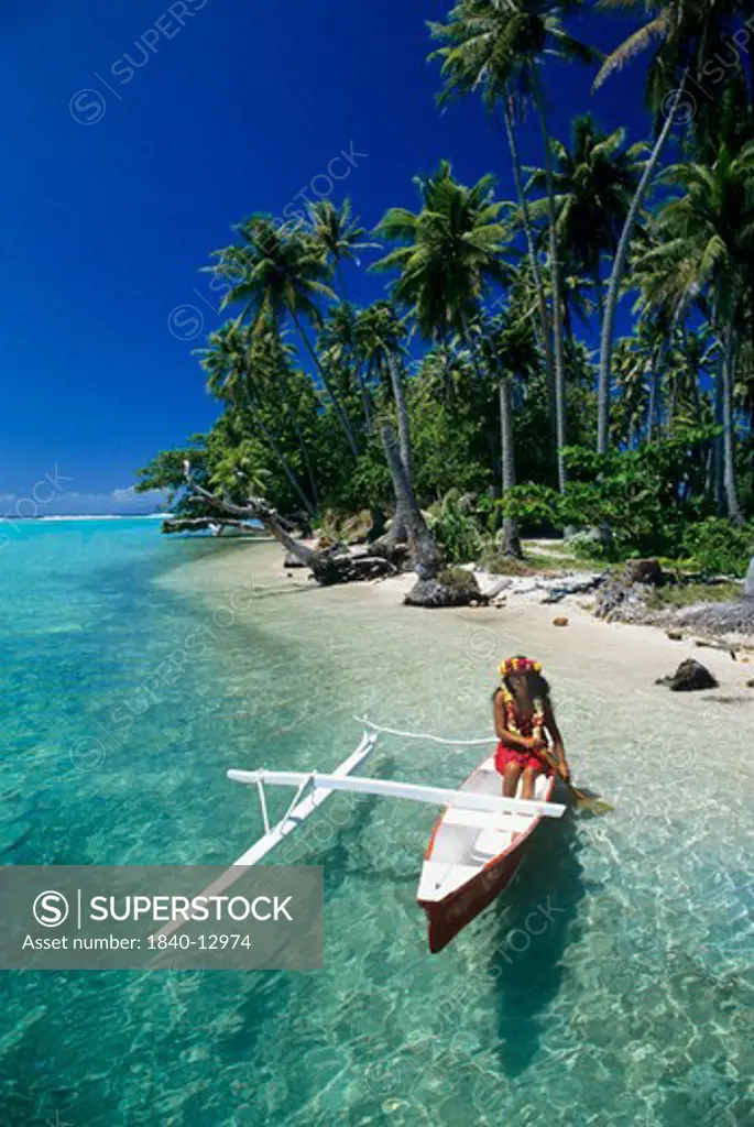 Woman paddling a traditional outrigger canoe in the lagoon of Raiatea in the Society Islands of French Polynesia.