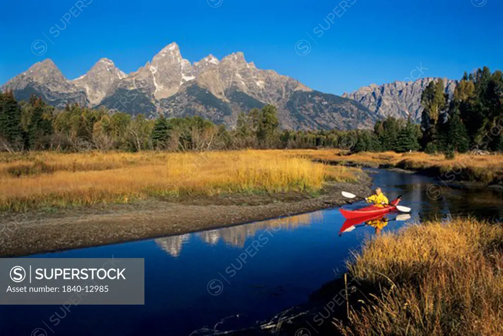 Kayaking on the Snake River at Swabacher's Landing below the Teton Range in Grand Teton National Park, Wyoming. As the highest peak in the range, Grand Teton rises 13,770' into the Wyoming sky just left of center at top.