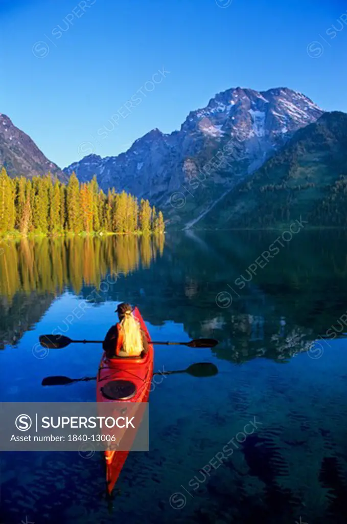 Woman kayaking on Leigh Lake beneath Mount Moran in Grand Teton National Park, Wyoming.