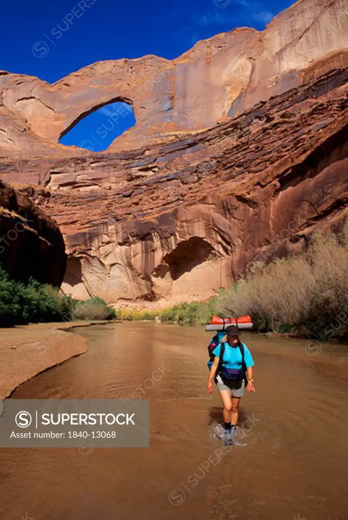 Hiking in the Escalante River below Steven's Arch at the mouth of Coyote Gulch, Escalante Canyons, Glen Canyon National Recreation Area, Utah.