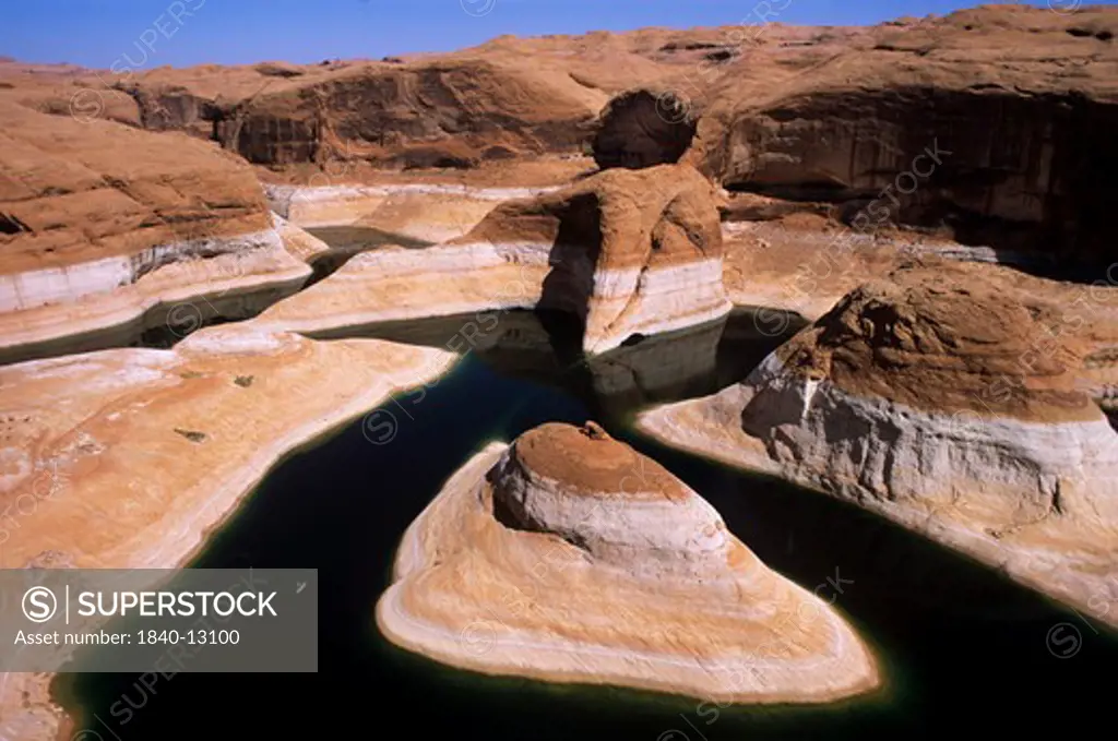 Kayaking (lower left) on Lake Powell in Reflection Canyon beneath 110-foot tall ""bathtub ring"" due to lowered level of reservoir resulting from a prolonged western drought which began in 1999.