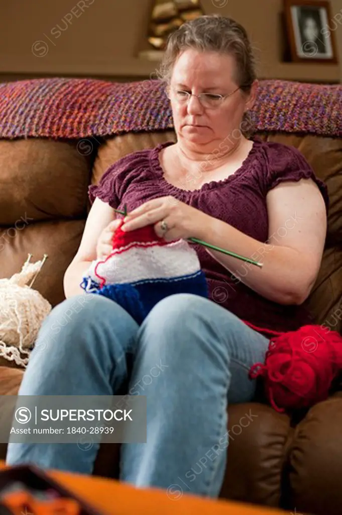 Mature woman on couch concentrating on her knitting