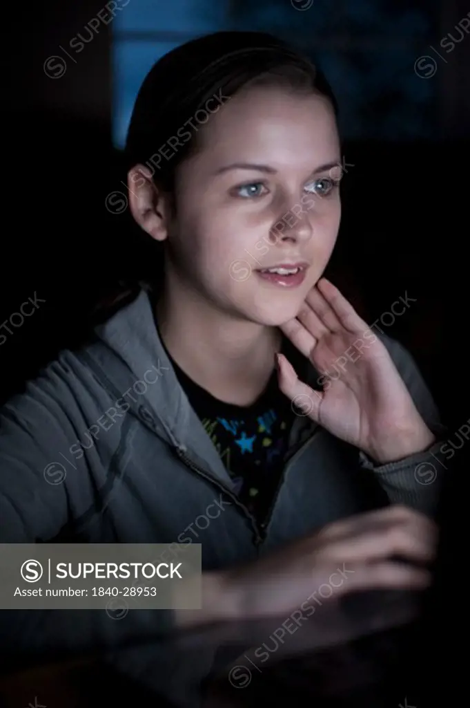 Teenager looking at computer screen in a darken living room