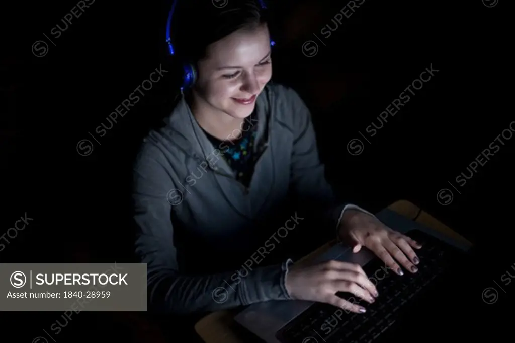 Teenager looking at computer screen in a darken living room