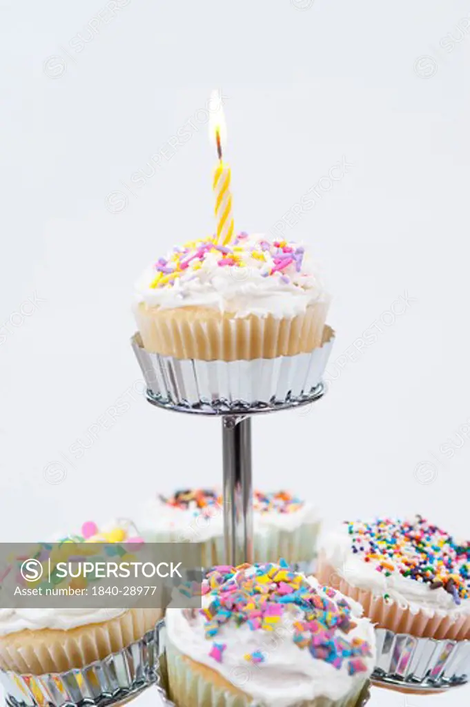 Cupcake stand with lit candle at top celebrating a special event