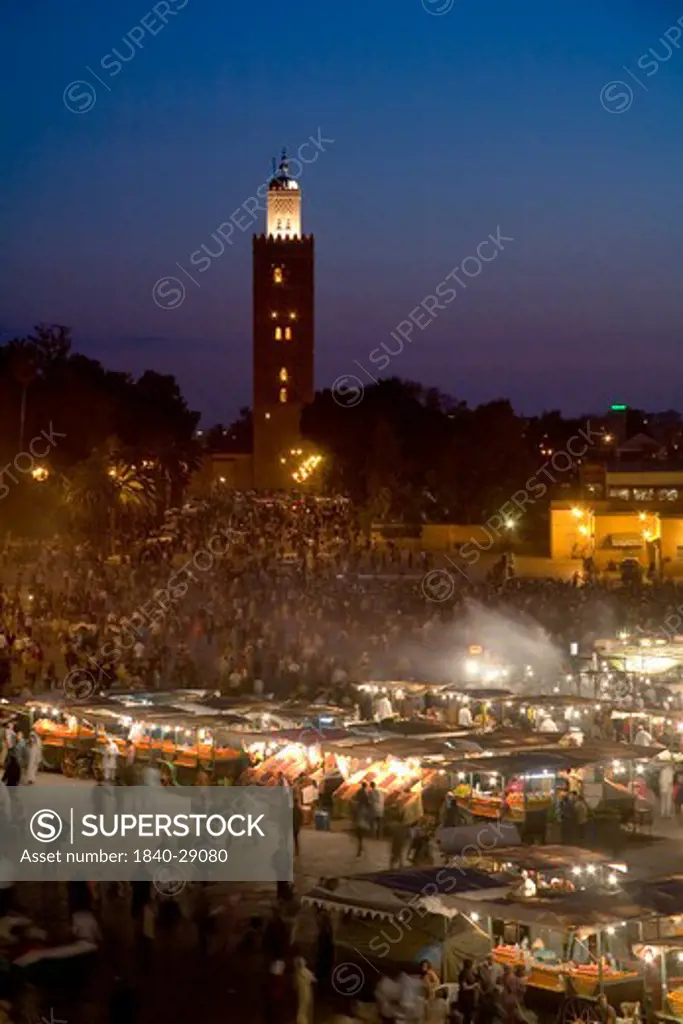 The La Koutoubia Mosque at Jemaa El Fna Square in Marrakech with food stalls and fruit sellers at nightime. Morocco