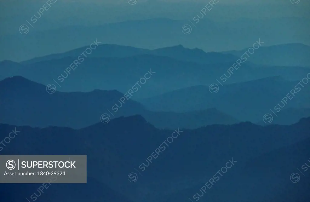 Distant mountain ridges in the Cascade Mountains of Washington state, taken from the 10,000 foot level on Mt. Rainier. With a clear view, one can see that most of these ridges are scarred from massive clearcuts common in this region.