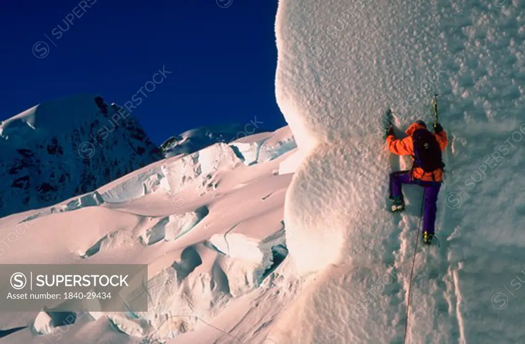 Ice climber scaling sheer icy cliff.