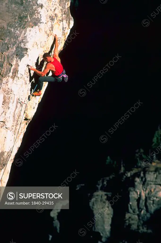 Rock climber hanging from sheer cliff.