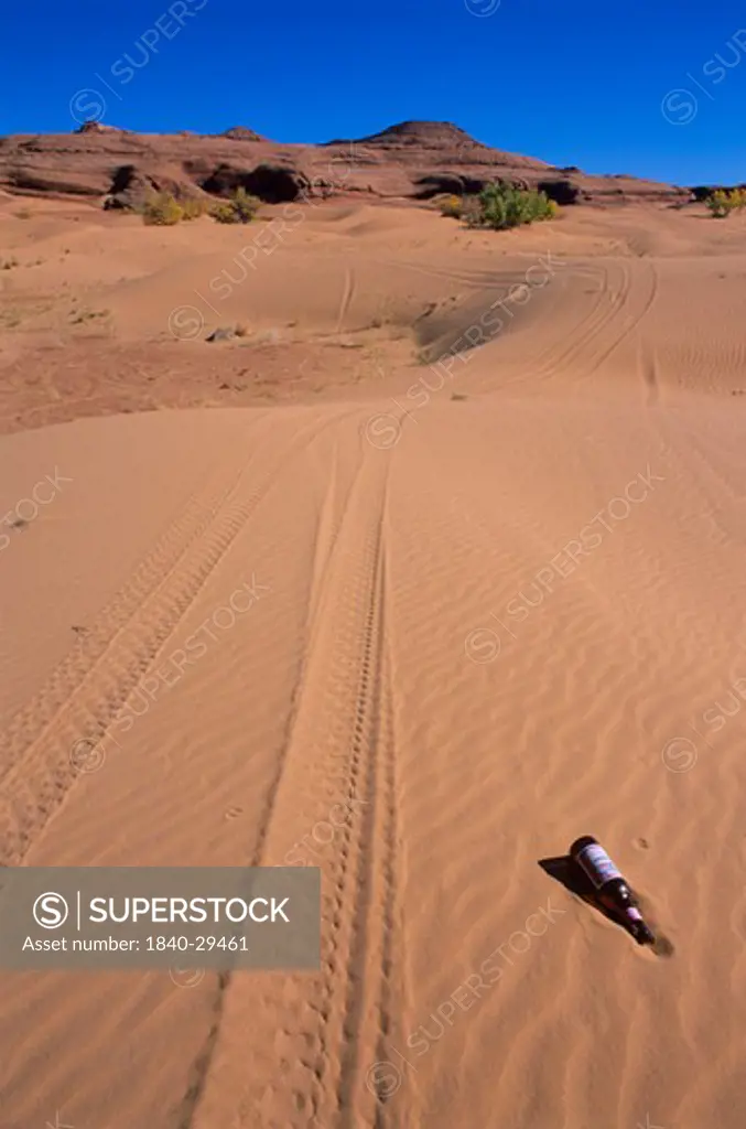 Off road vehicle tracks and beer bottle in the White Wash Dunes south of the town of Green River, Utah.