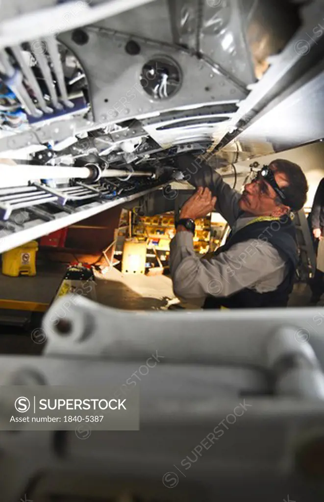 mechanic installing an aileron control cable during a C-check