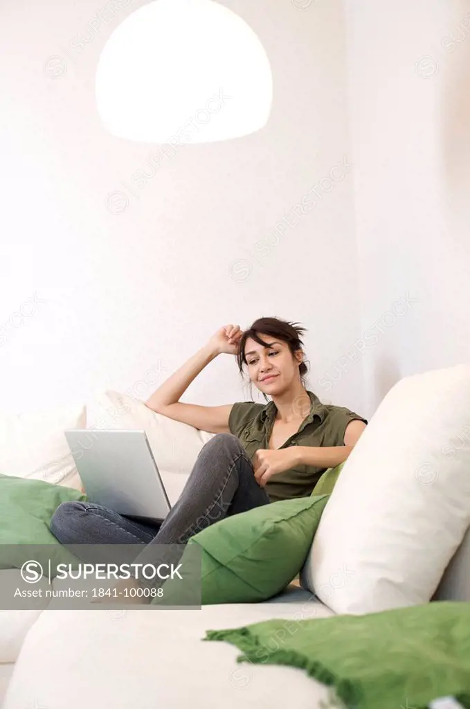 Content woman in living room with laptop