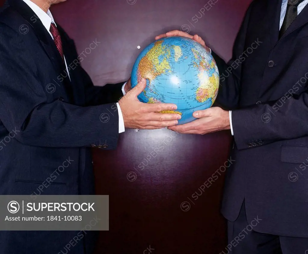 Mid section view of two businessmen holding globe