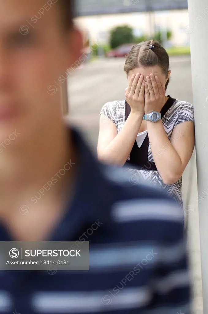 Close_up of teenage boy with his sobbing friend in background