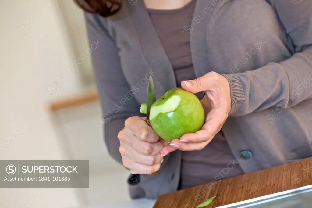 Woman peeling apple in kitchen, close_up