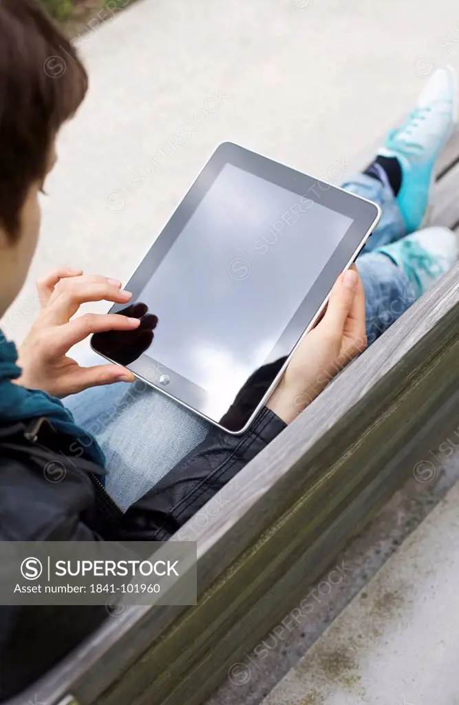 Young woman using iPad on a bench