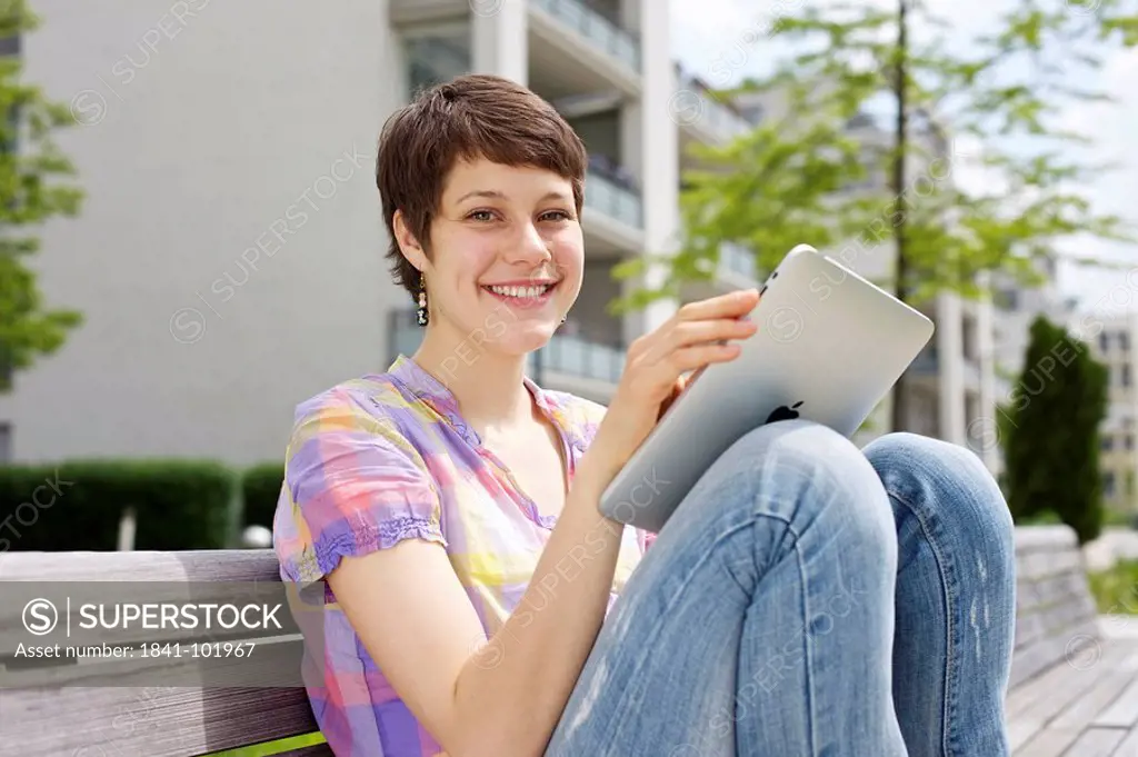 Young woman using iPad on a bench