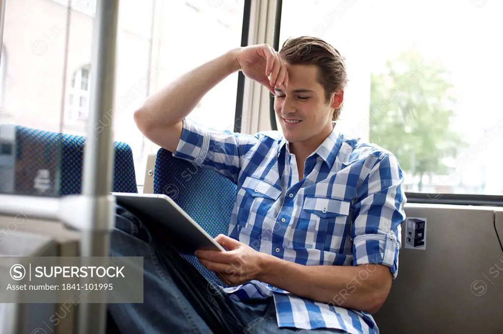 Young man using iPad in tram
