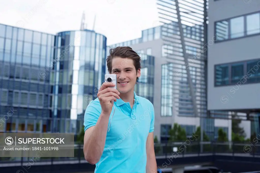 Young man with smartphone in front of office building