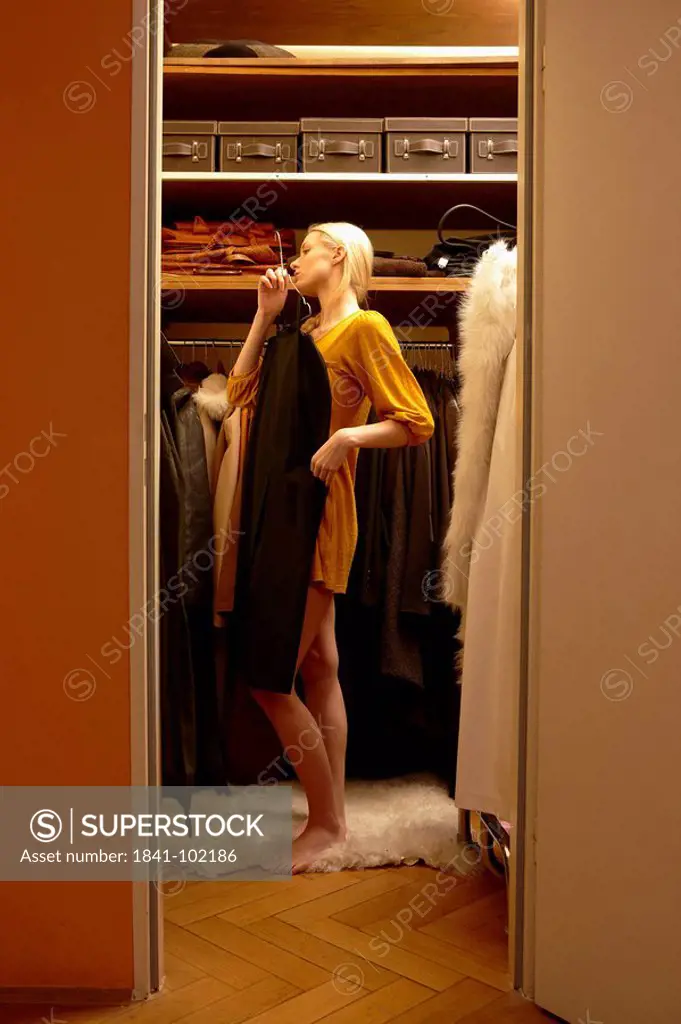 Young woman choosing dress from wardrobe